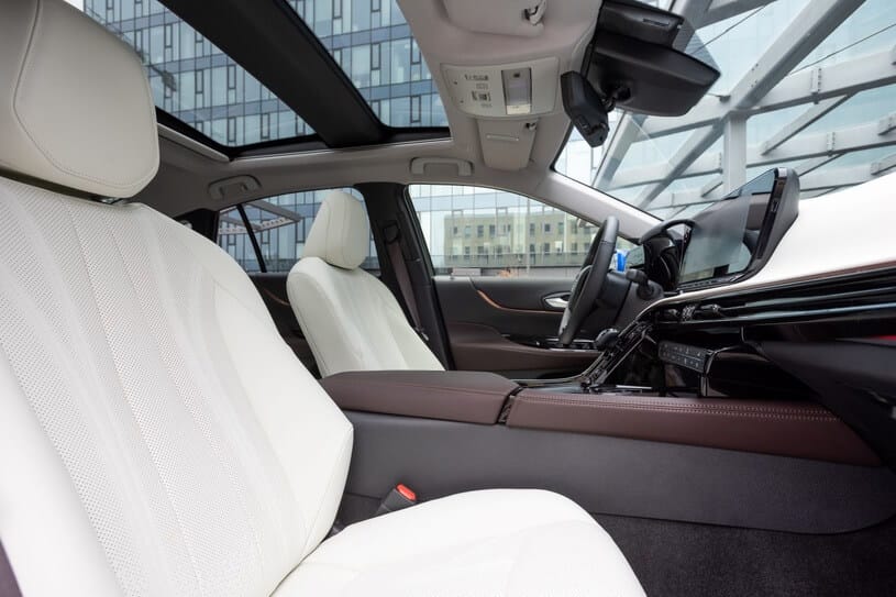 Wnętrze Toyoty Mirai: białe skórzane fotele, panoramiczny dach, cyfrowy kokpit.