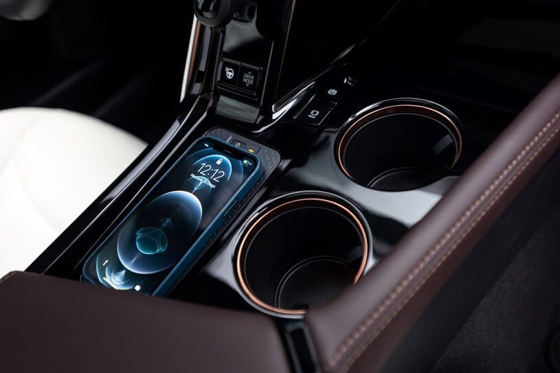 Smartfon na konsoli środkowej Toyoty Mirai obok dwóch pustych uchwytów i białego fotela.