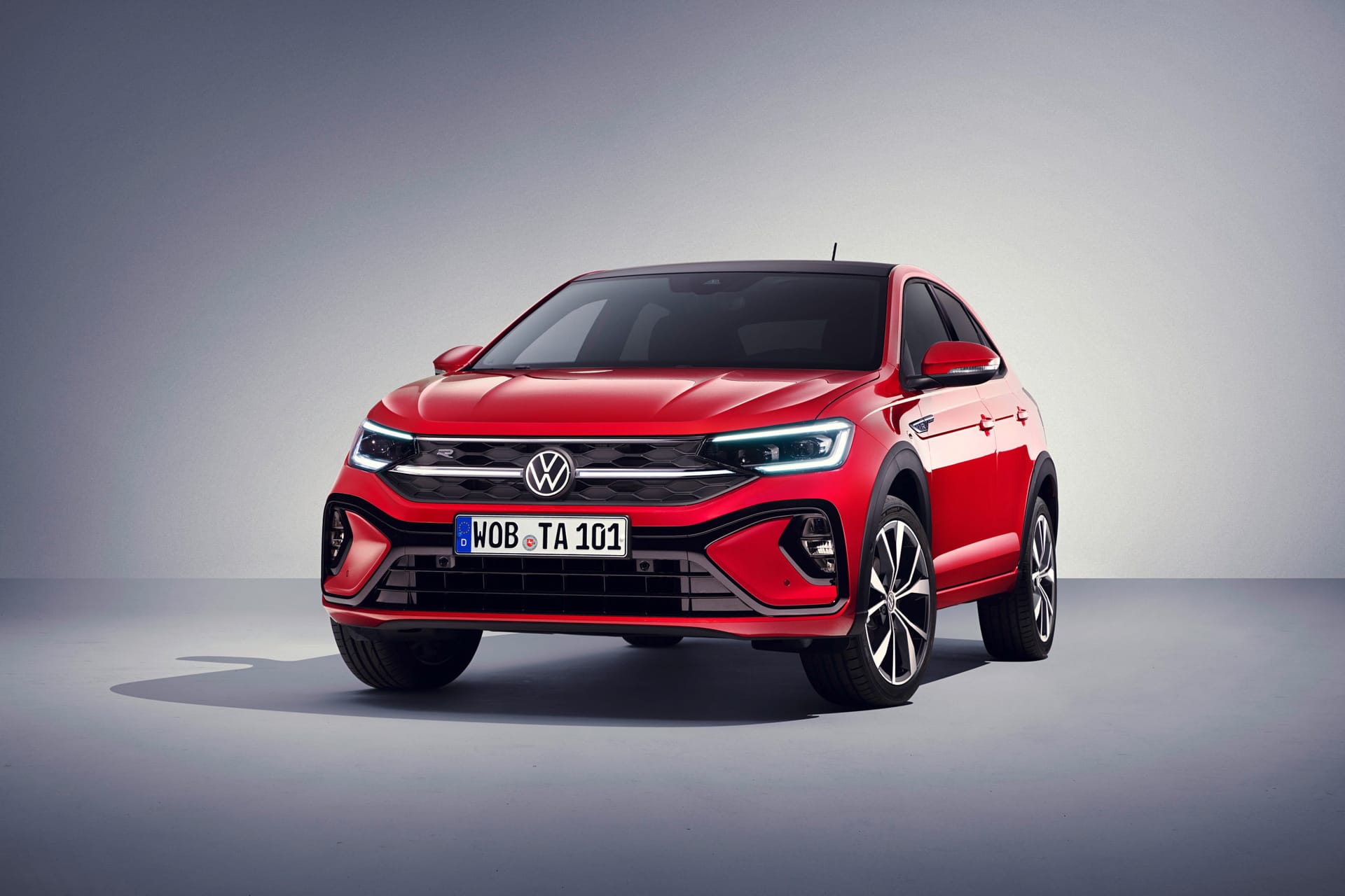 Czerwony SUV Volkswagen Taigo stoi w studiu na szarym tle, przodem skierowanym w prawo.