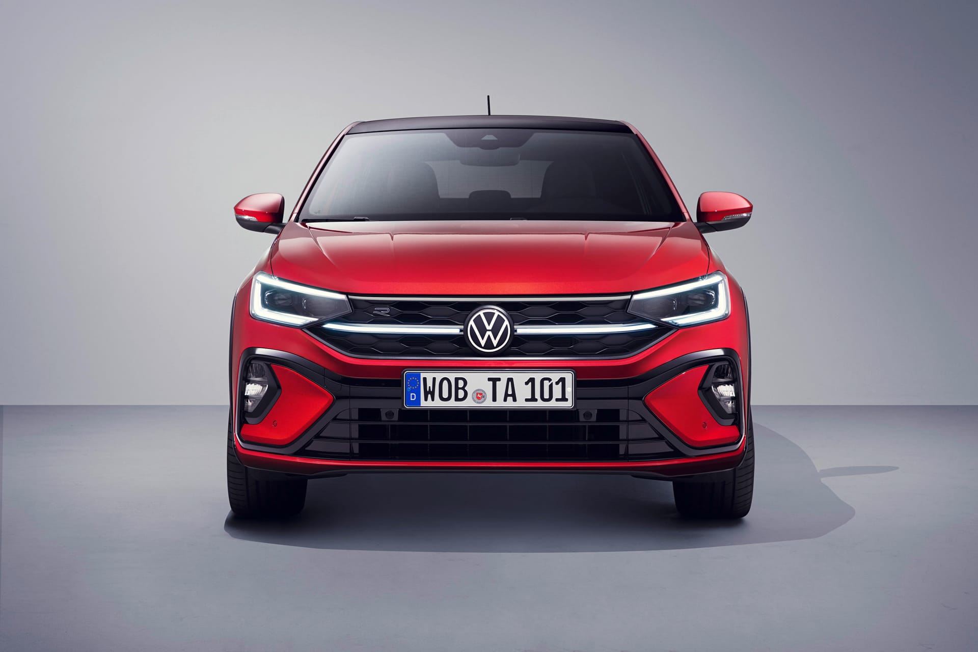 Czerwony Volkswagen Taigo z reflektorami LED i tablicą rejestracyjną WOB TA 101 w studiu.