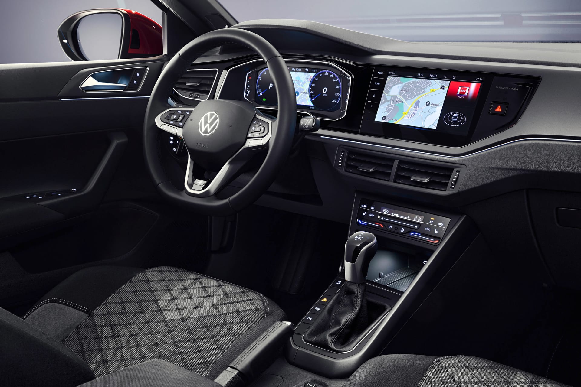 Wnętrze Volkswagena Taigo: kierownica, cyfrowy kokpit, ekran dotykowy, dźwignia zmiany biegów, czarne fotele.