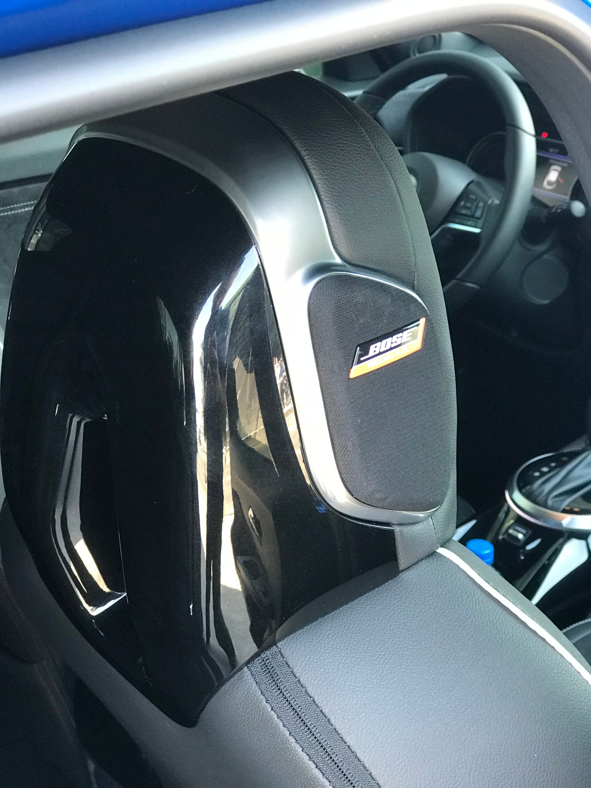 Zagłówek przedniego fotela w samochodzie Nissan Juke Hybrid z głośnikiem Bose; widoczna kierownica.