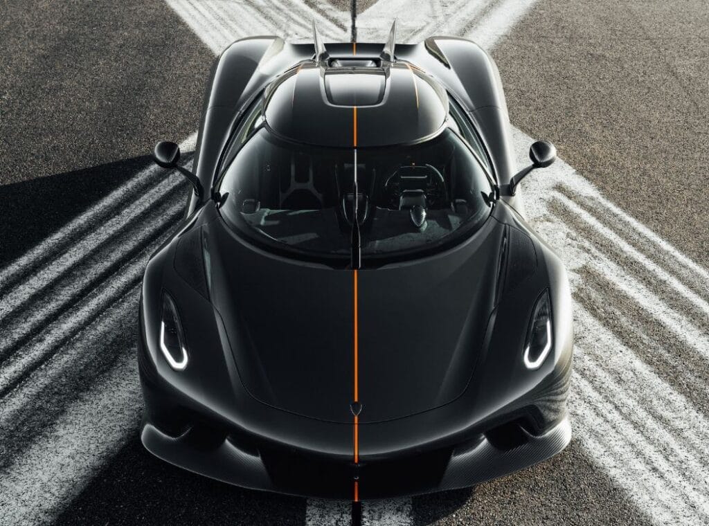 Czarny Koenigsegg Jesko Absolut z pomarańczowym paskiem stoi na jezdni, na której widnieje znak X.
