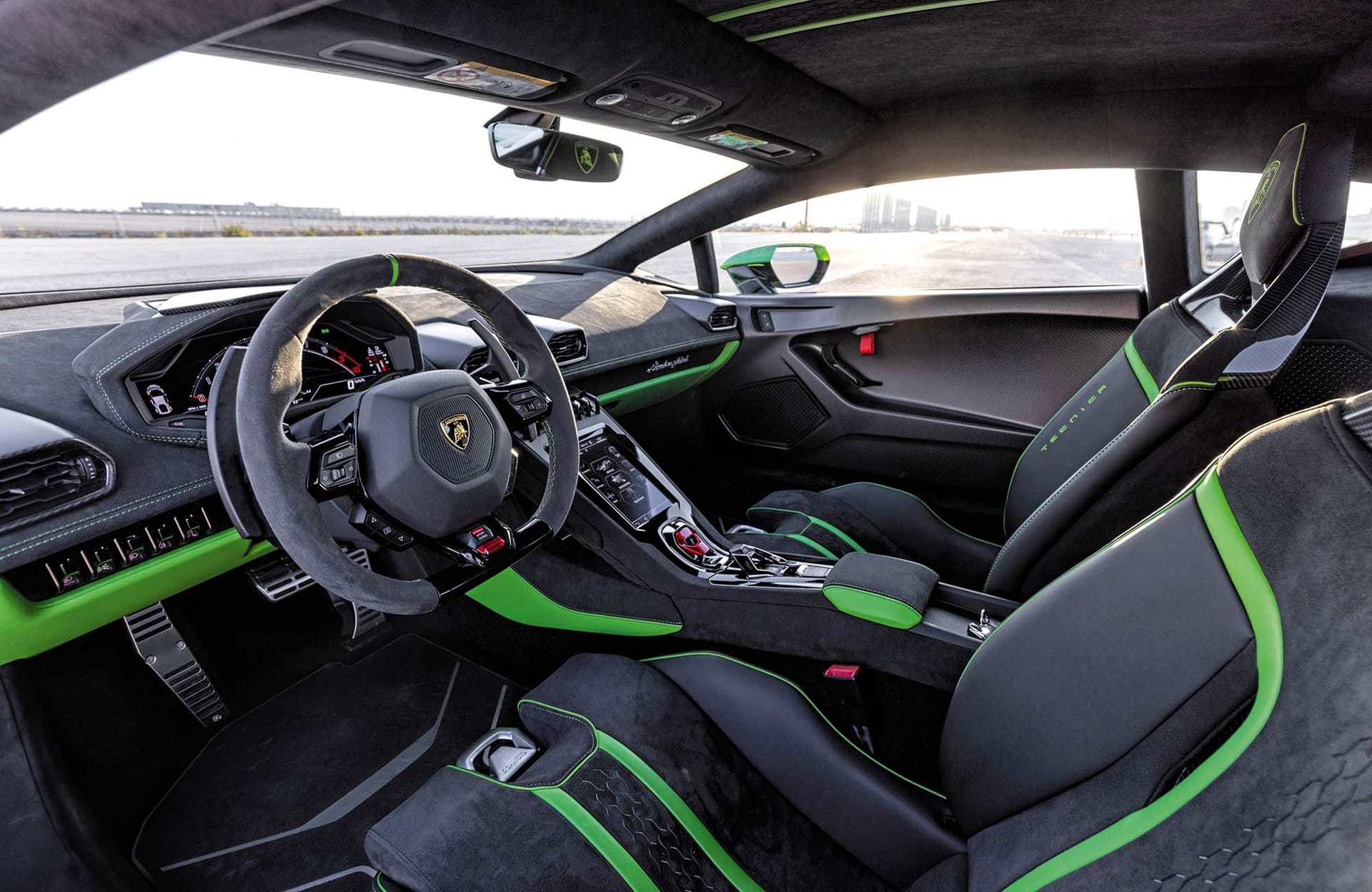 Wnętrze Lamborghini Huracan Tecnica: czarno-zielone fotele, kierownica, deska rozdzielcza i konsola środkowa.
