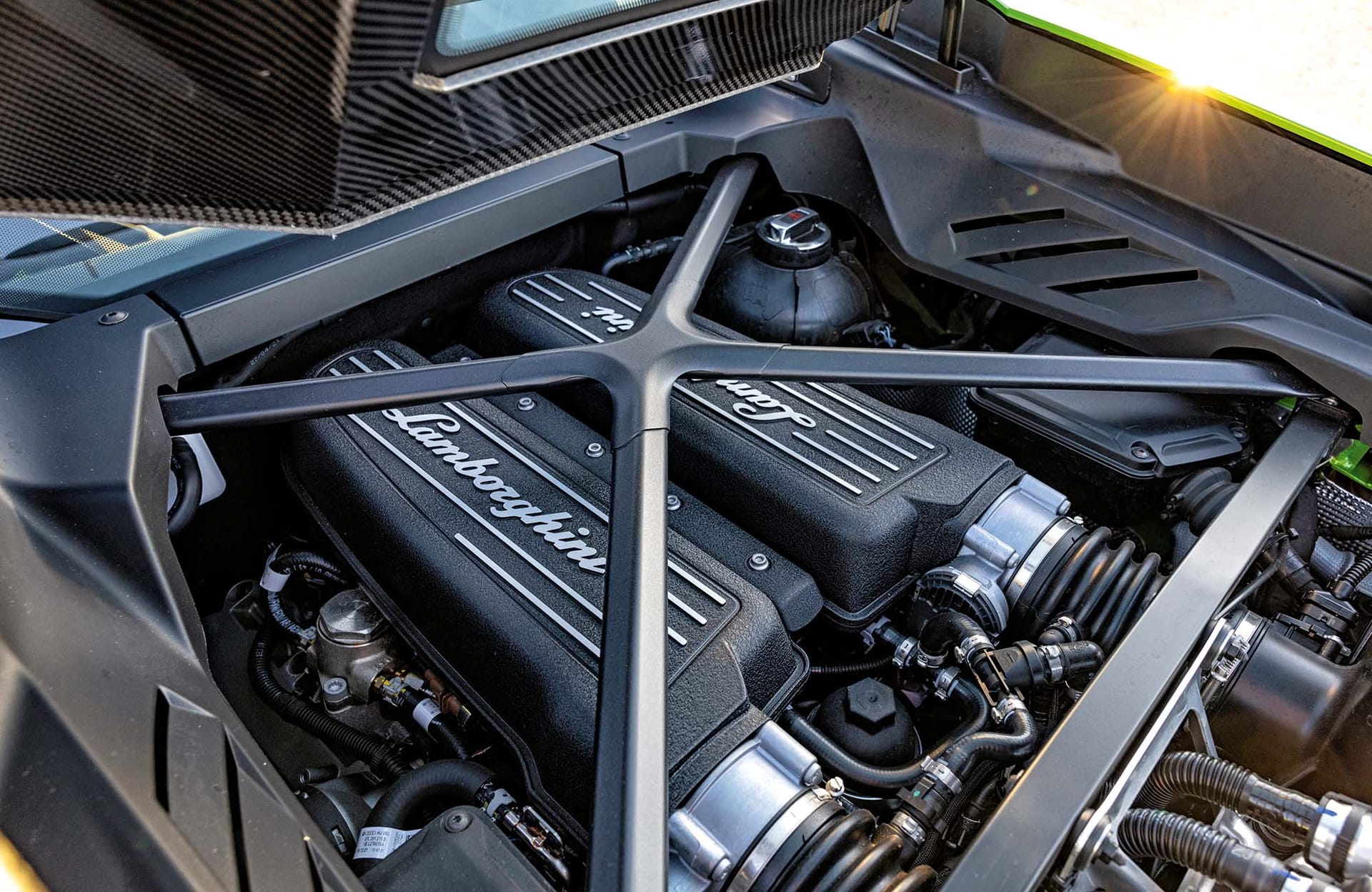 Silnik Lamborghini Huracan Tecnica z czarnymi osłonami i logo, z metalowym wzmocnieniem nad nimi.