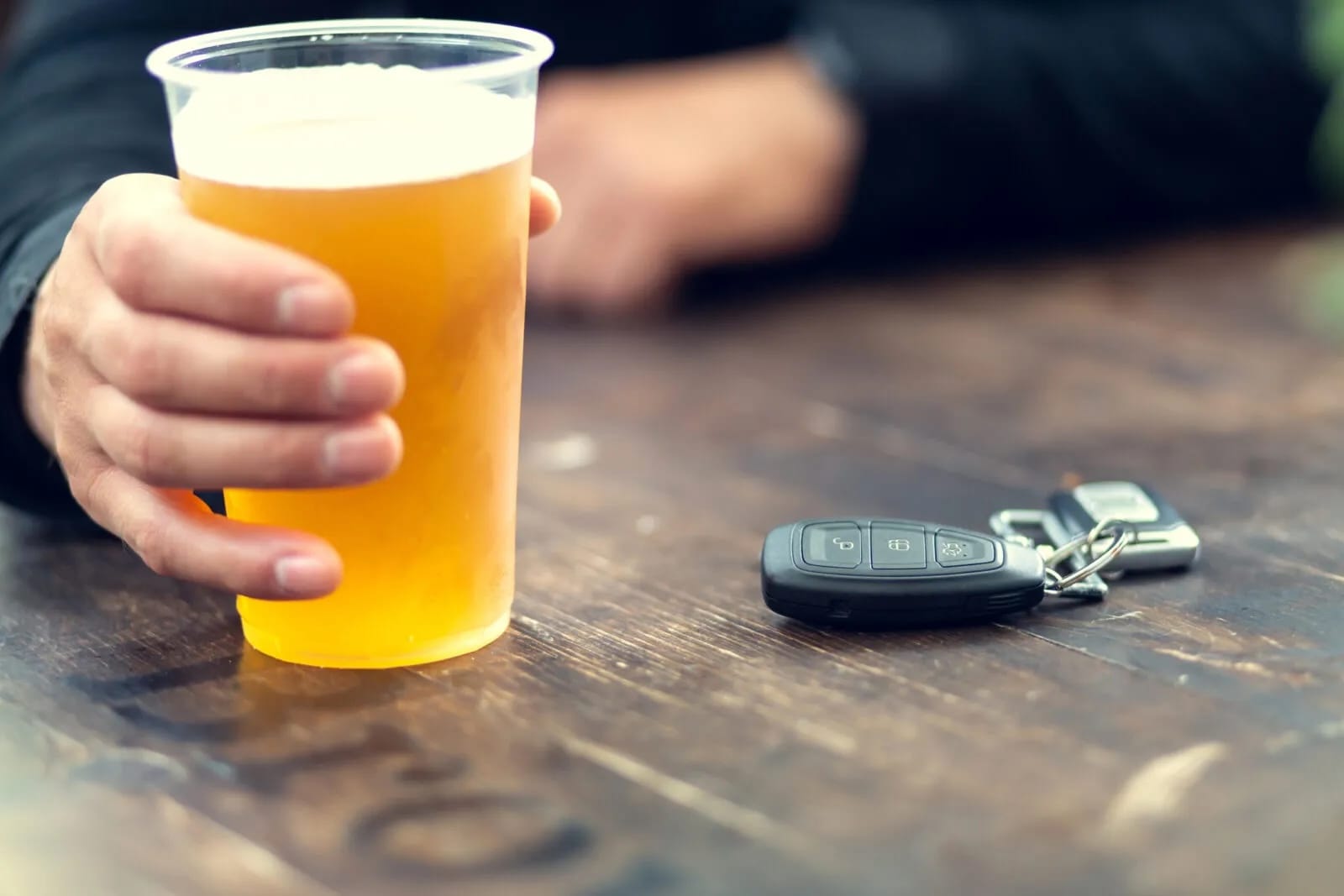 ręka sięga po piwo na stole leżą klucze do samochodu