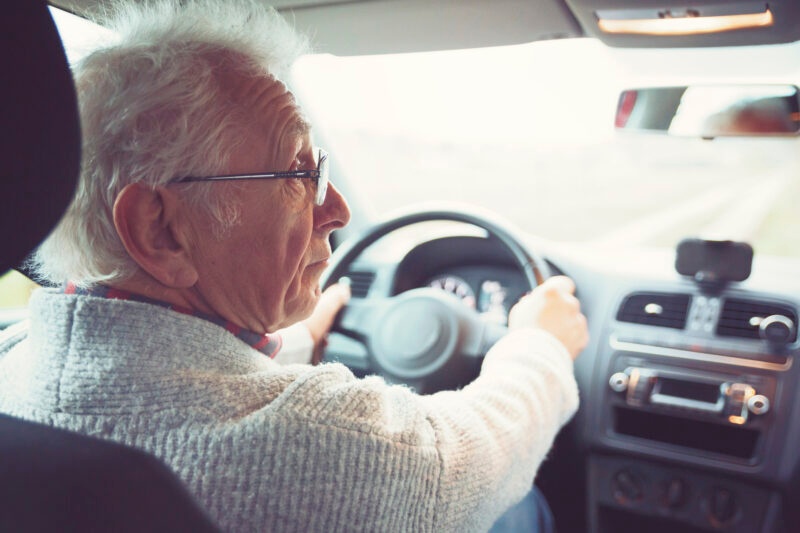 starszy mężczyzna prowadzi auto osobowe