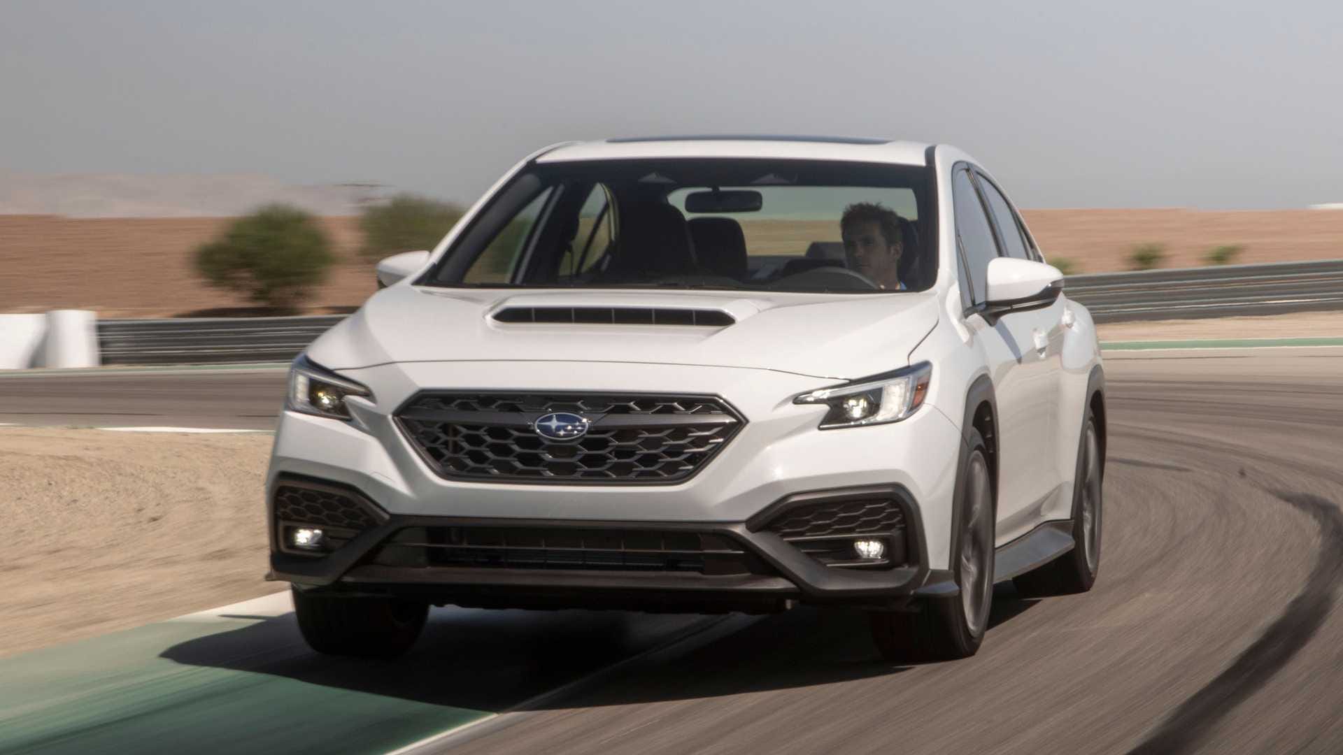 Białe Subaru WRX skręca na torze wyścigowym pod gołym niebem.