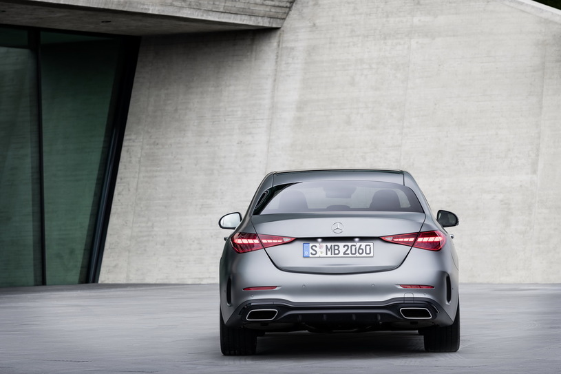 Srebrny Mercedes klasy C stoi na betonie przed nowoczesnym budynkiem z dużymi oknami.