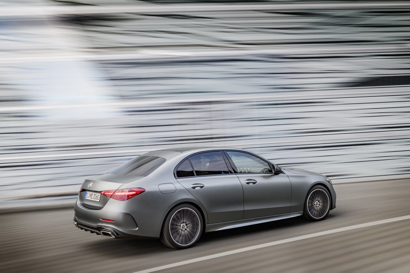 Srebrny Mercedes klasy C jedzie po drodze, a rozmyte tło podkreśla ruch.