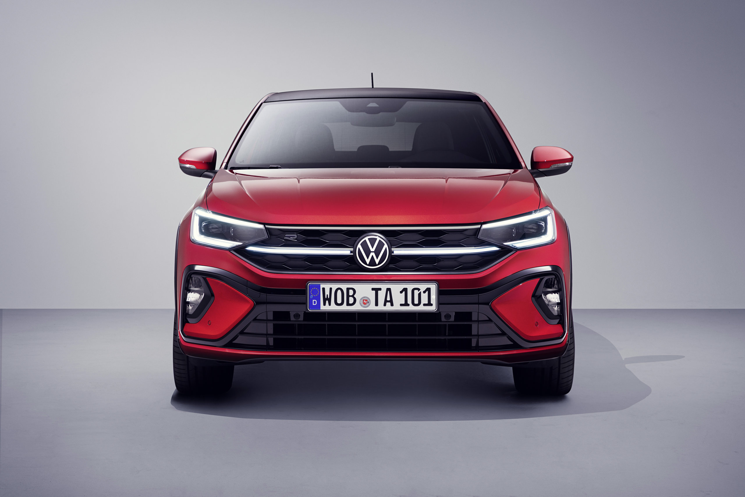 Czerwony Volkswagen Taigo z reflektorami LED i tablicą rejestracyjną WOB TA 101 w studiu.