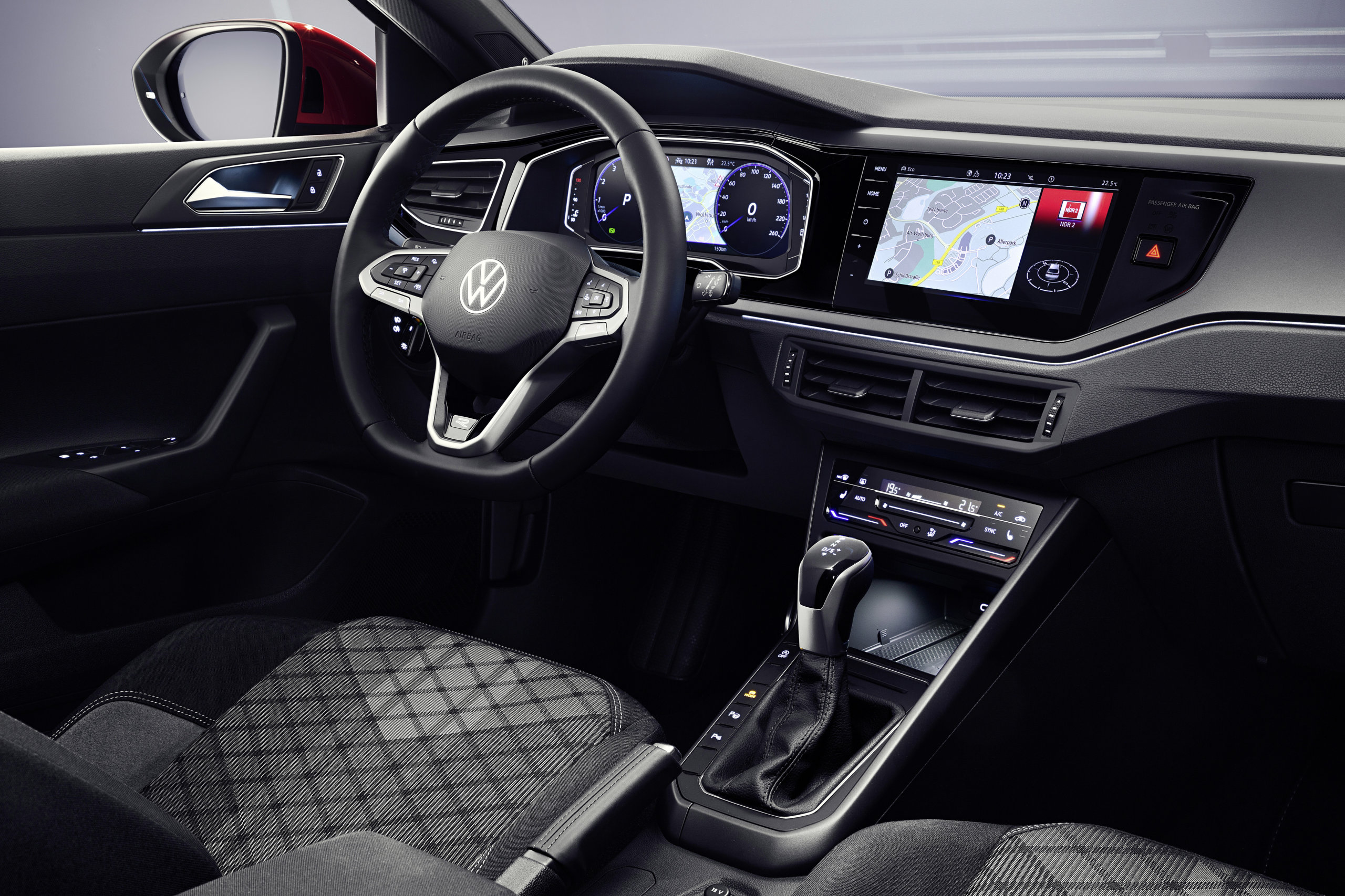 Wnętrze Volkswagena Taigo: kierownica, cyfrowy kokpit, ekran dotykowy, dźwignia zmiany biegów, czarne fotele.