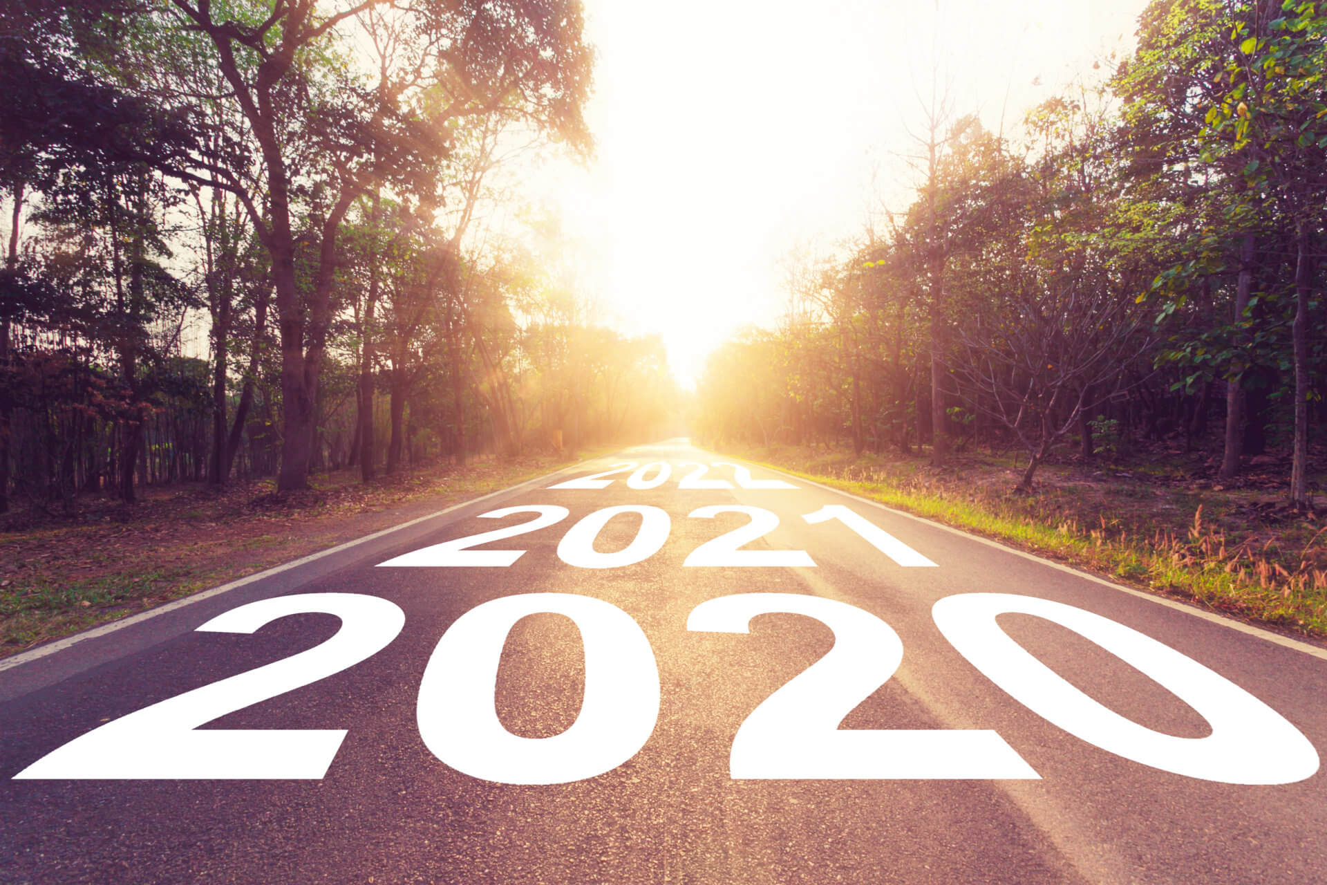 Asfaltowa droga z lat 2020 i 2021 prowadzi w stronę jasnego wschodu słońca.