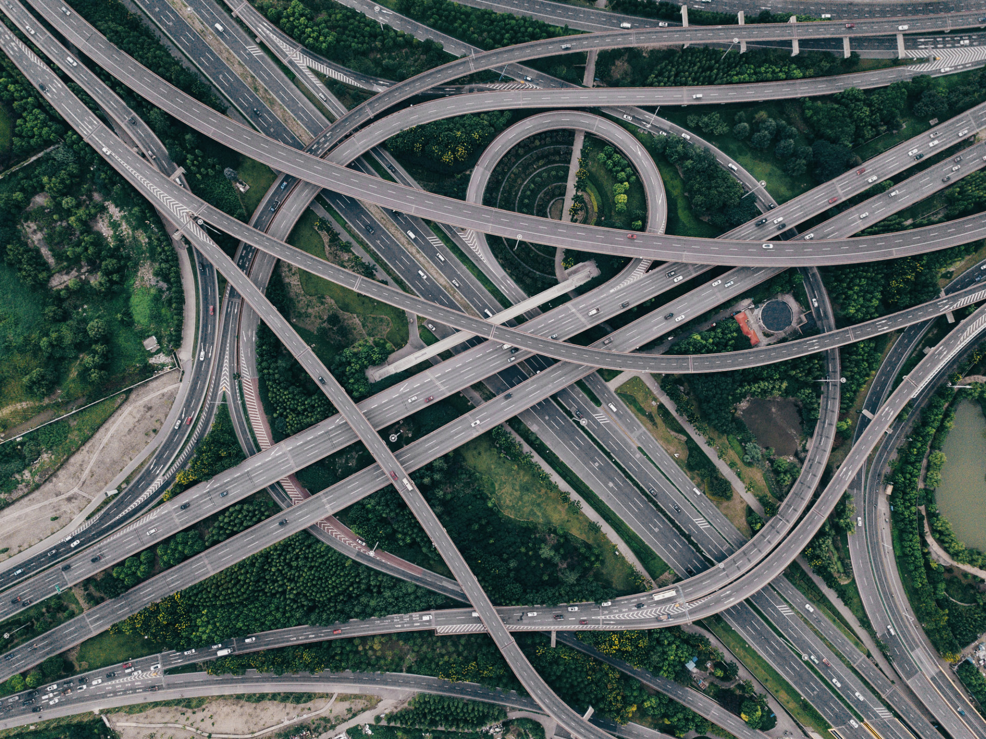 Skrzyżowanie autostrad z licznymi estakadami pośród zielonych terenów, widok z lotu ptaka.