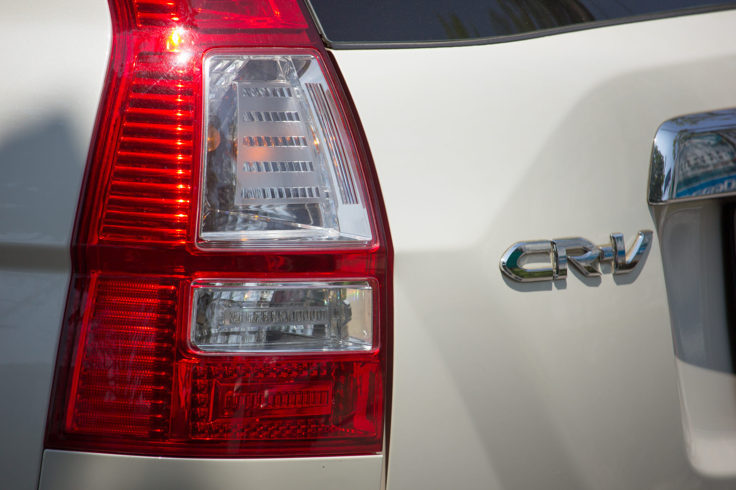 Tył samochodu z beżowym lakierem, tylnym światłem i chromowanym emblematem Honda CR-V.