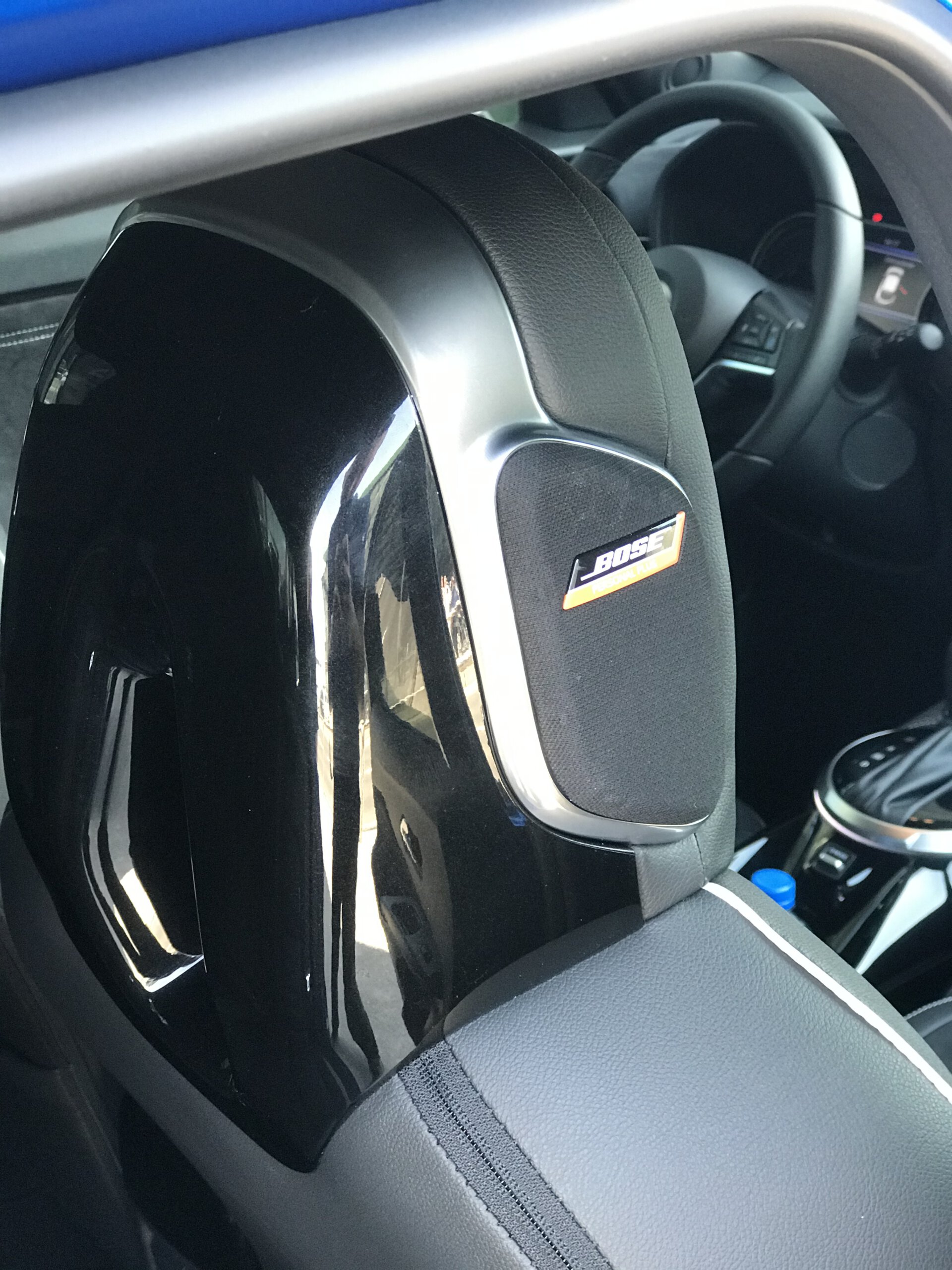 Zagłówek przedniego fotela w samochodzie Nissan Juke Hybrid z głośnikiem Bose; widoczna kierownica.