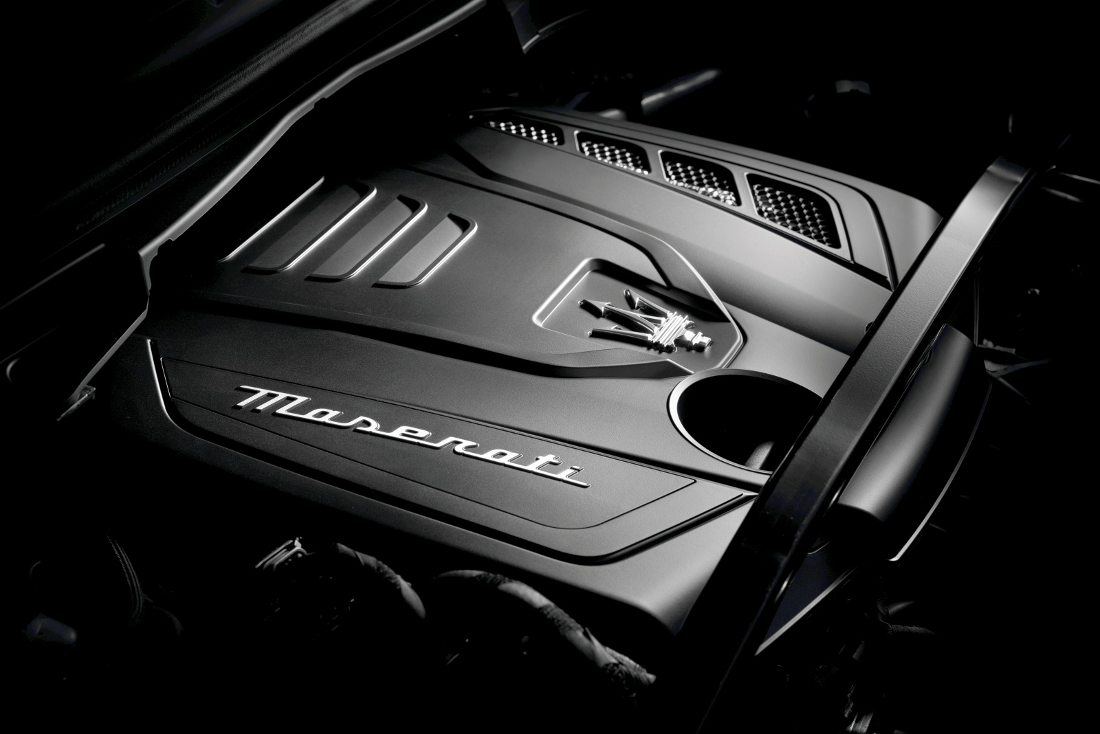 Pokrywa silnika Maserati Grecale z logo i napisem na ciemnym, eleganckim tle.