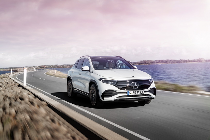 Biały Mercedes EQA jedzie nadmorską drogą, po prawej stronie woda, po lewej skały.