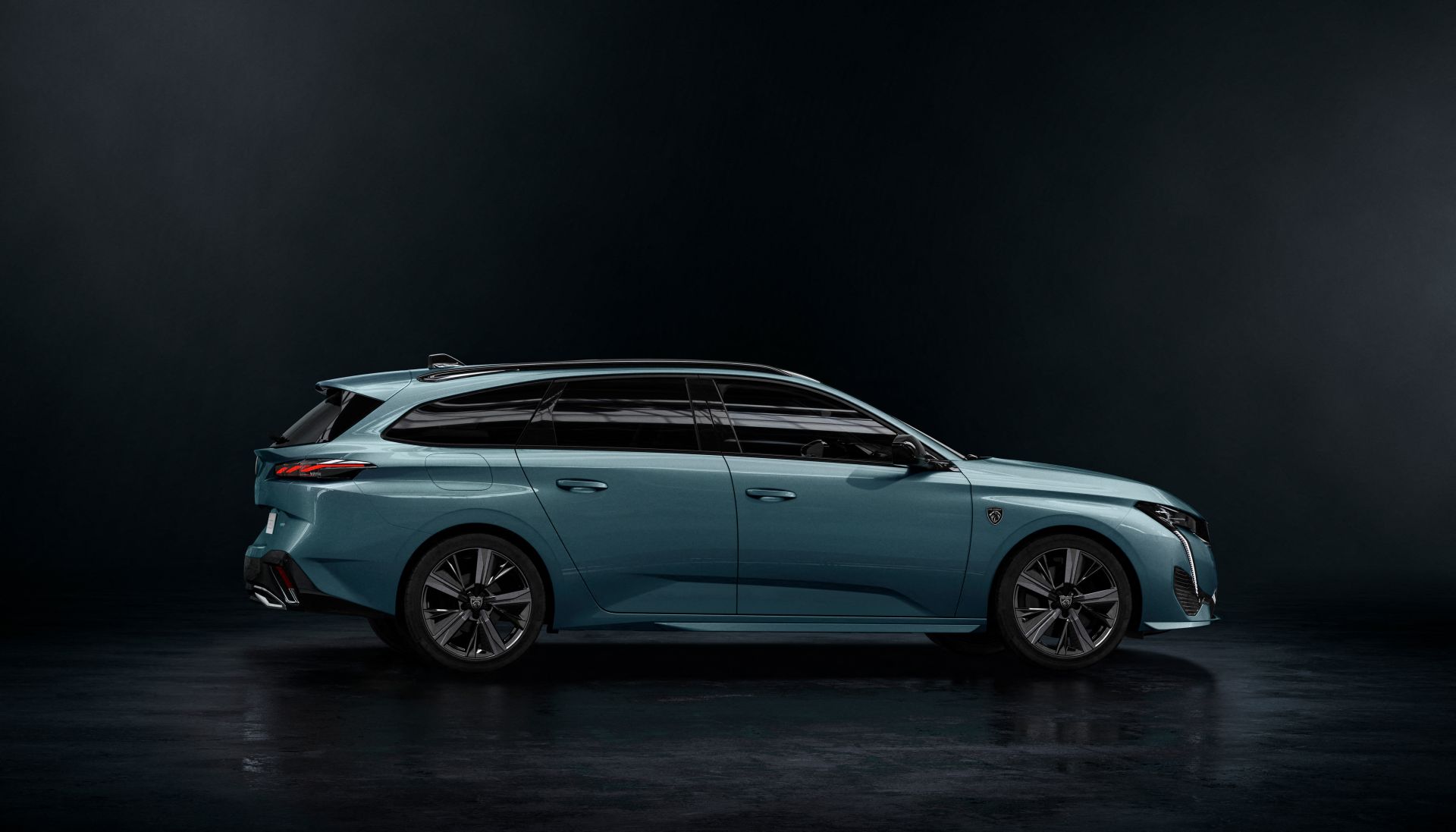 Niebieski Peugeot 308 SW kombi widziany z boku na ciemnym tle studyjnym.