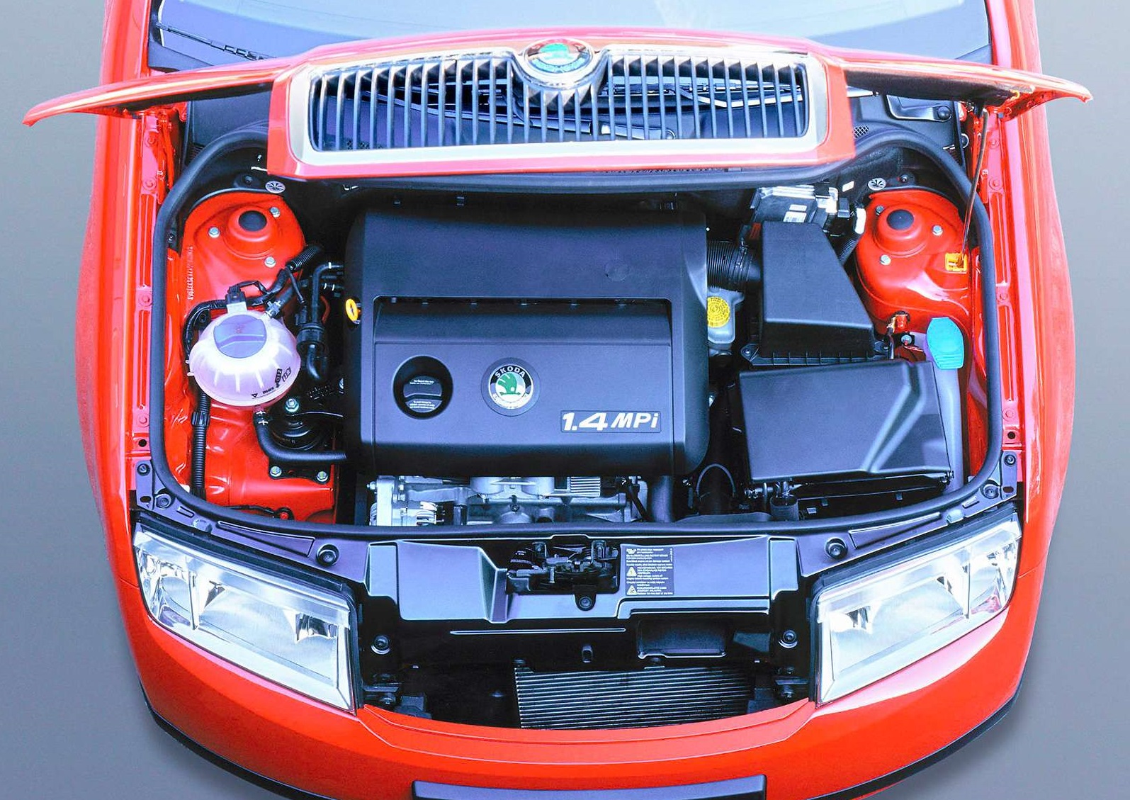 Skoda Fabia z otwartą maską, czysty silnik 1.4 MPI w czerwonej komorze silnika.
