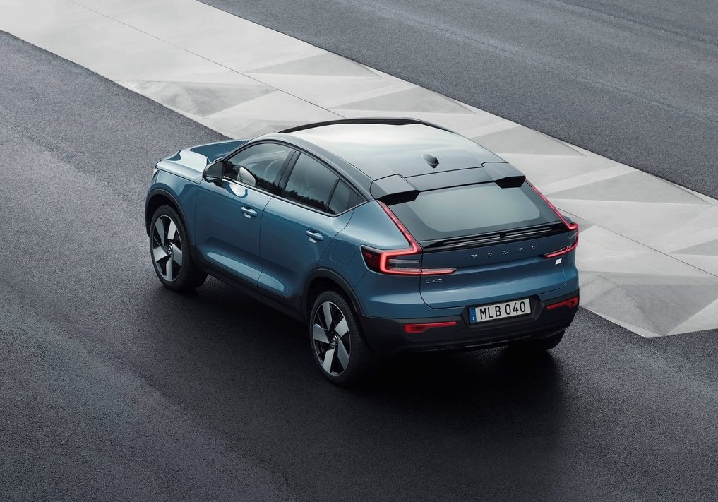 Niebieskie Volvo C40 Recharge stoi na ciemnej nawierzchni obok jasnego, geometrycznego chodnika.