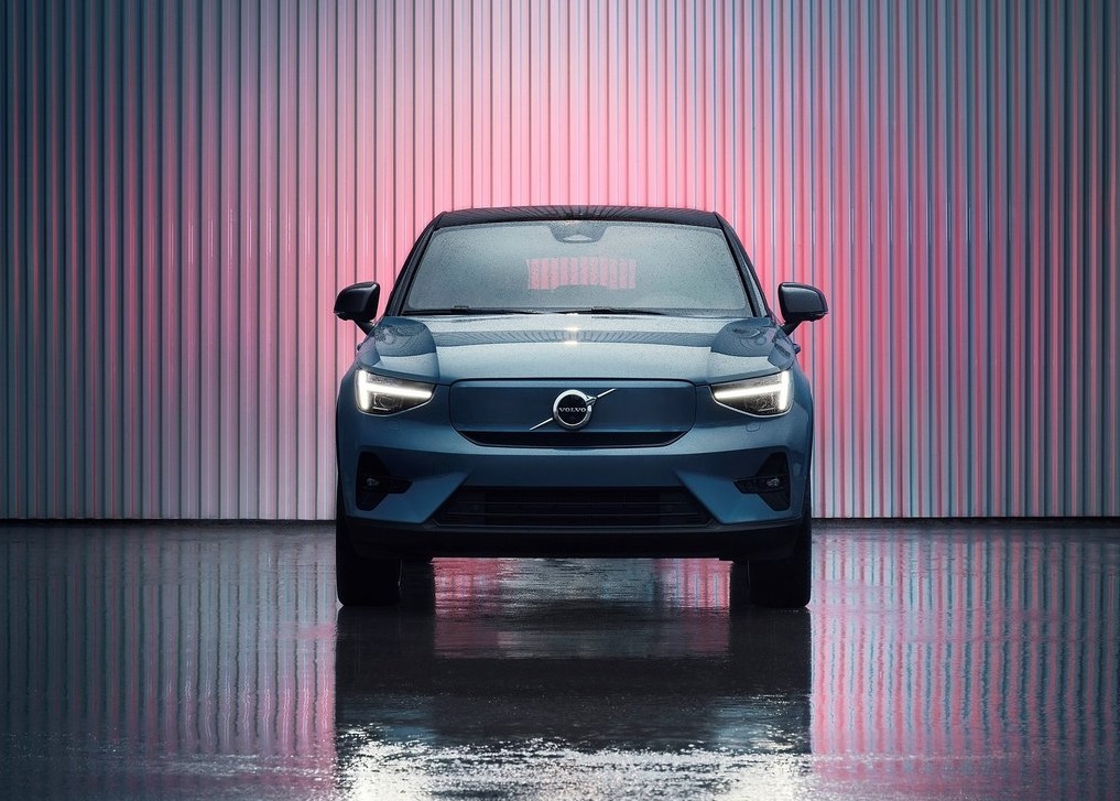 Niebieskie Volvo C40 stoi w pomieszczeniu na tle paneli rozświetlonych różowo-niebieskim światłem.