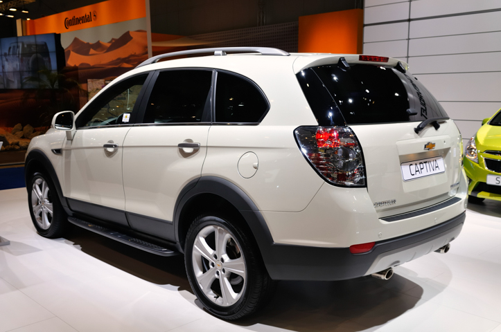 Biały SUV Chevrolet Captiva na wystawie salonowej, widziany z tyłu po lewej stronie.