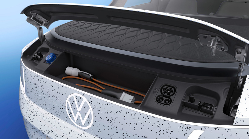Otwarty bagażnik Volkswagena ID.Life z kablem do ładowania i gniazdami, na niebieskim tle.