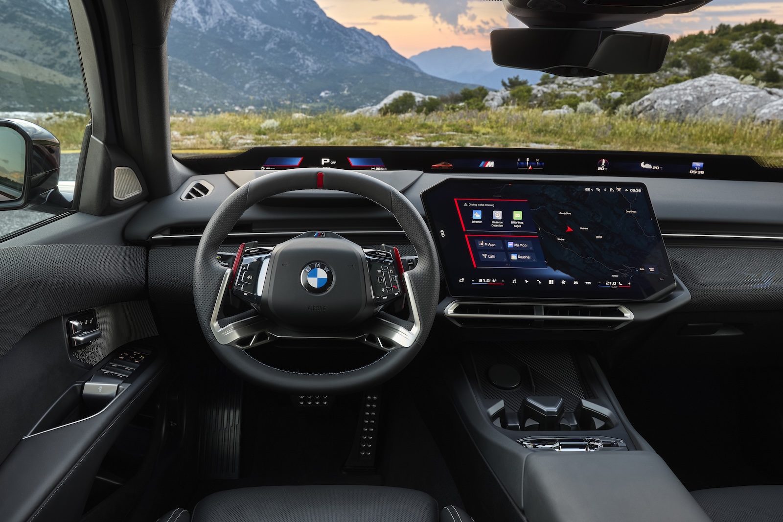 Wnętrze BMW z cyfrowym kokpitem, kierownicą wielofunkcyjną i widokiem na góry.