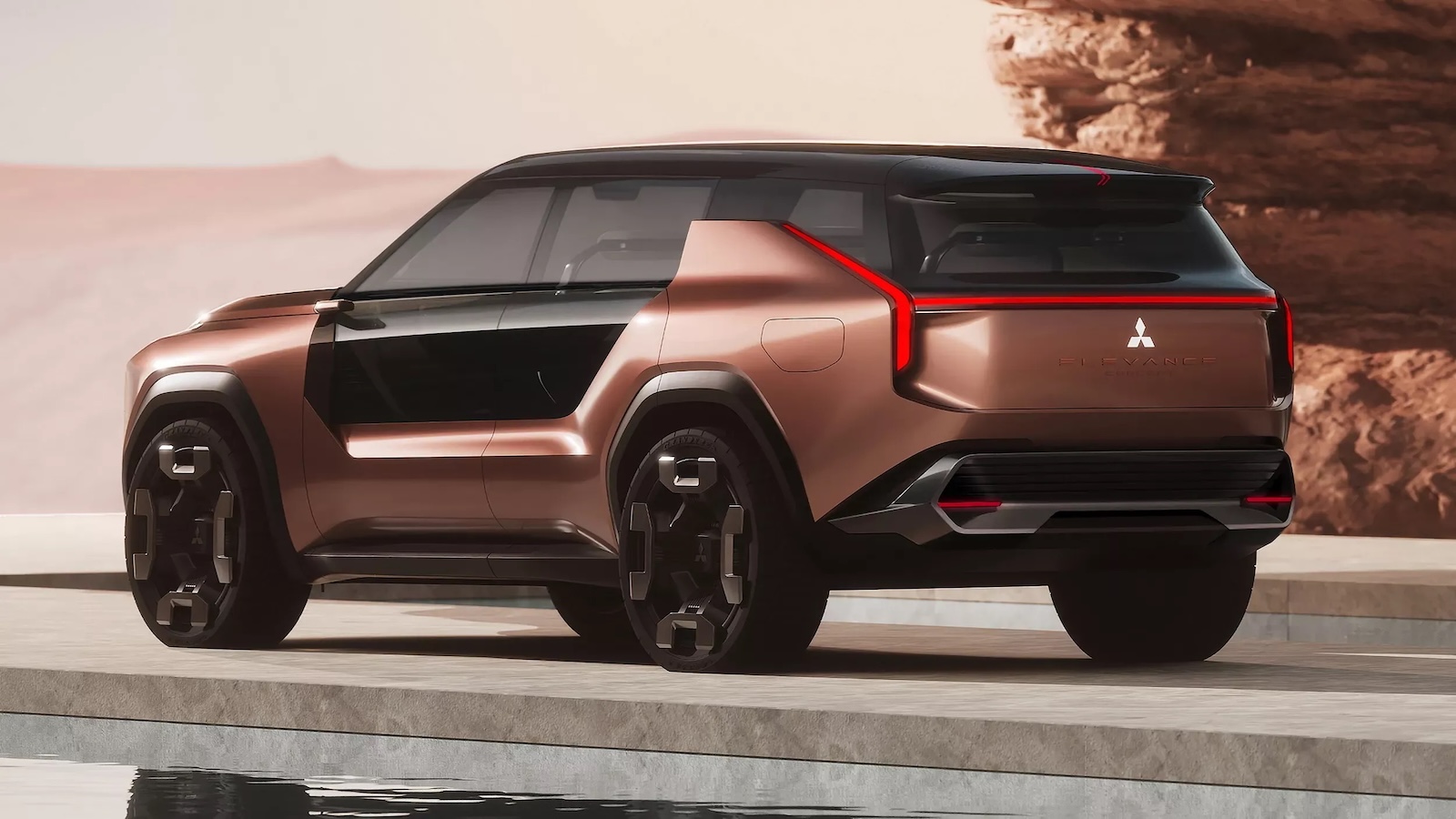 Brązowy prototyp SUV-a marki Mitsubishi z czarnymi akcentami stoi przy basenie na skalistej pustyni.