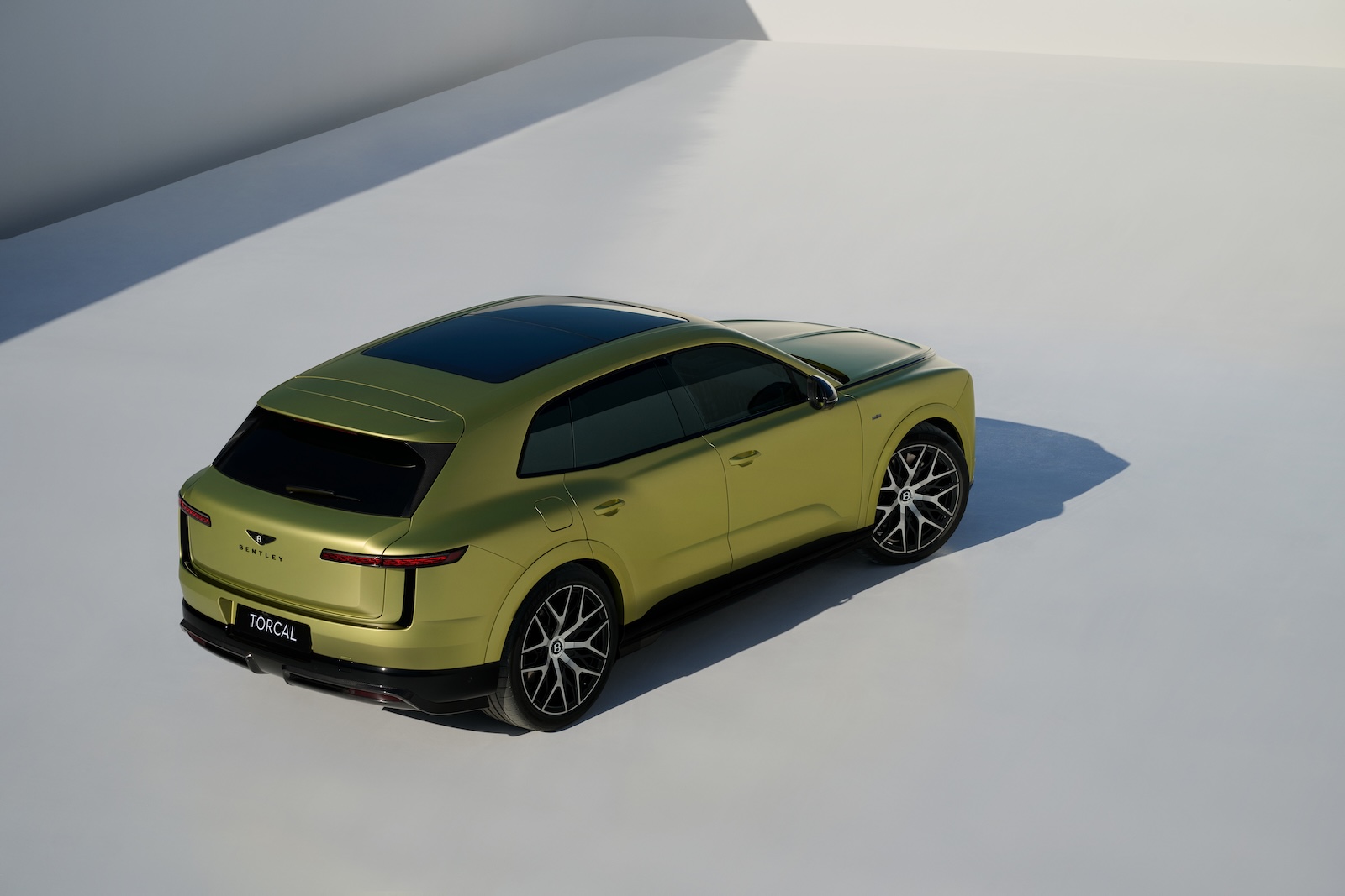 Jasnozielony SUV Genesis o eleganckim wyglądzie, widziany z góry na białym tle.