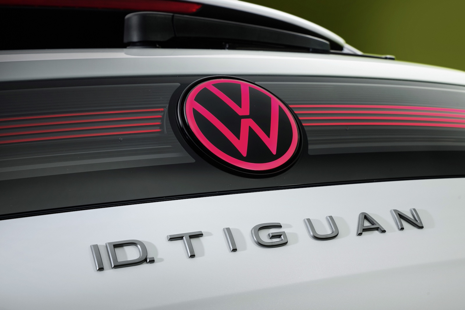 Tył Volkswagena ID. Tiguan z różowo-czarnym logo VW nad nazwą modelu na białym tle.