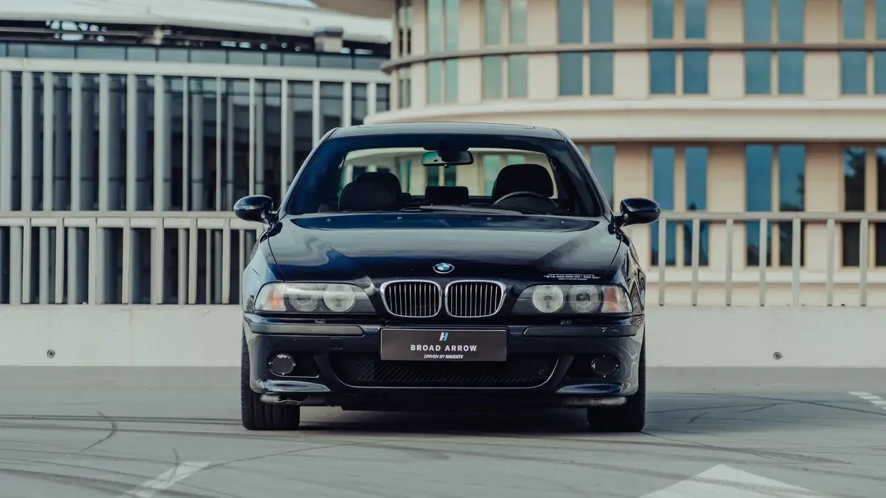 Czarny sedan BMW zaparkowany na zewnątrz, a w tle nowoczesne budynki.