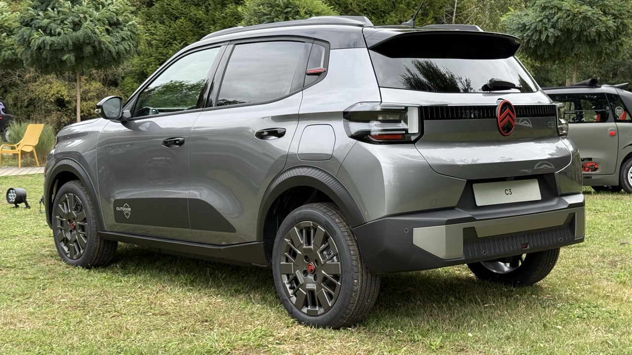 Szary SUV Citroën C3 stoi na trawie, a w tle widać drzewa i inny samochód.