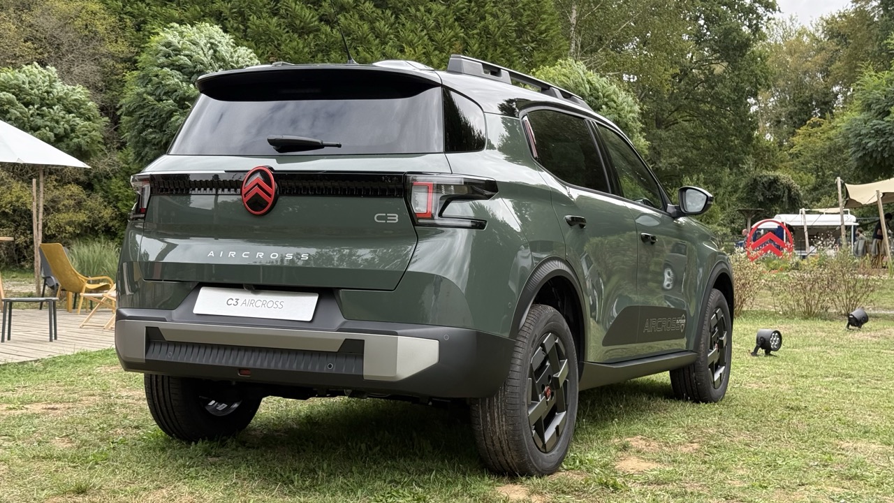 Zielony Citroën C3 Aircross stoi na trawie, a w tle widać drzewa i meble ogrodowe.