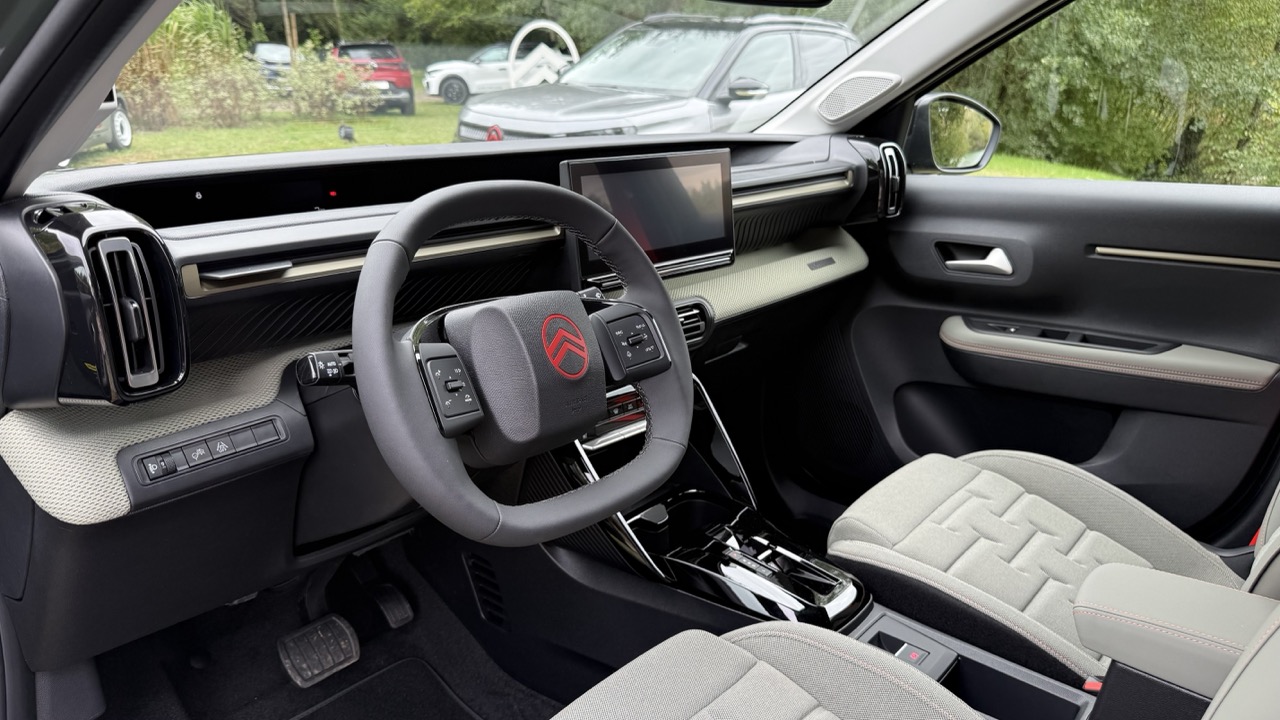 Wnętrze Citroëna: kierownica, deska rozdzielcza z ekranem, dźwignia zmiany biegów, dwa fotele.