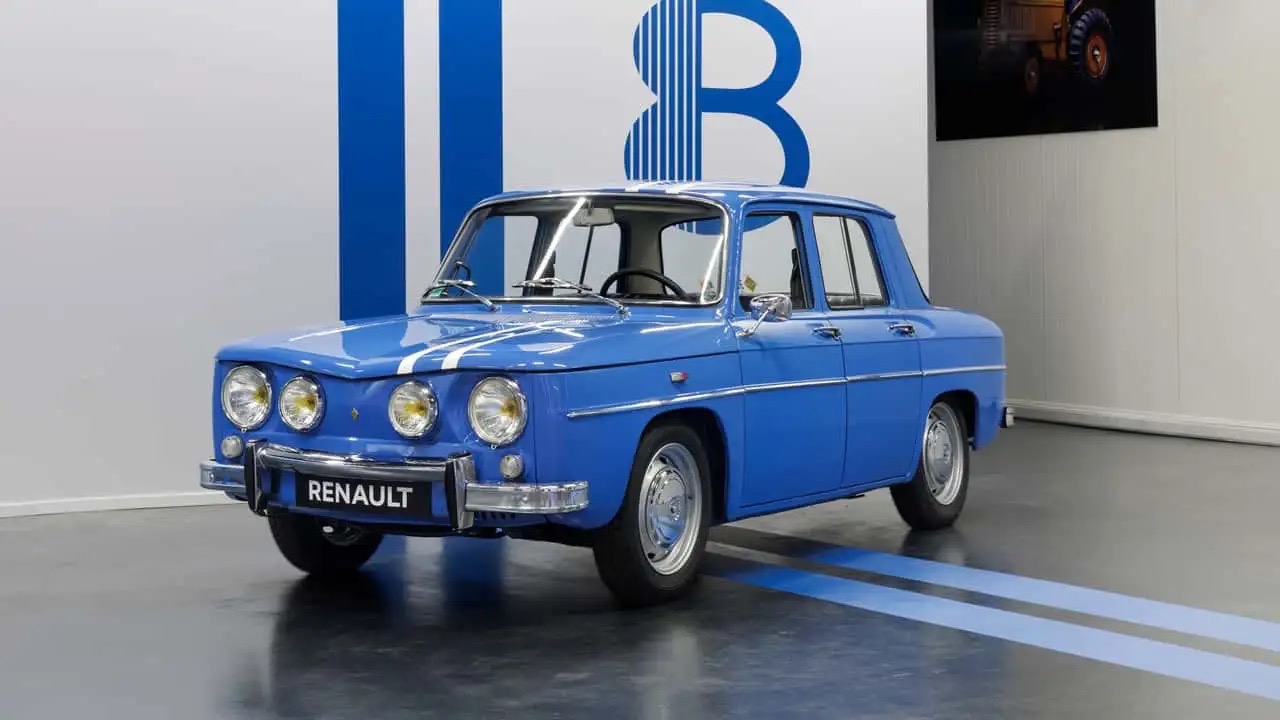 Klasyczne niebieskie Renault stoi na szarej podłodze z niebieskimi pasami przy ścianie B.