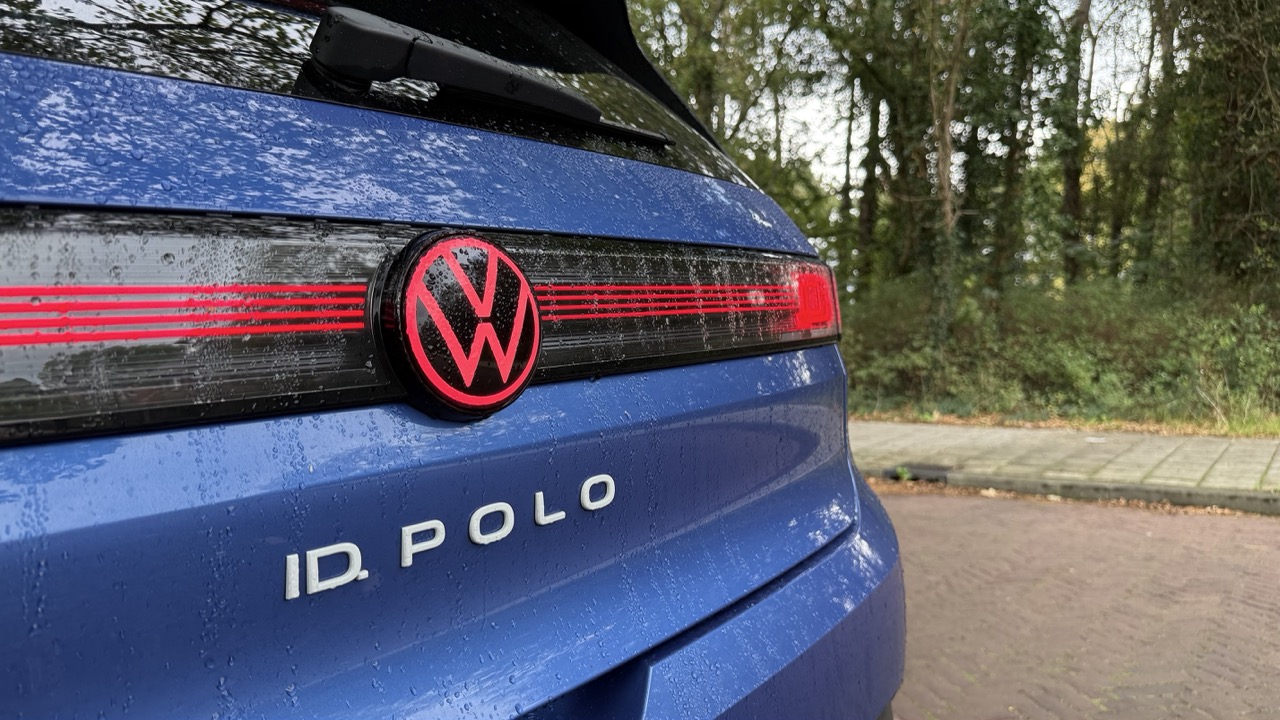Tył niebieskiego Volkswagena ID. Polo na mokrym asfalcie, w tle drzewa.