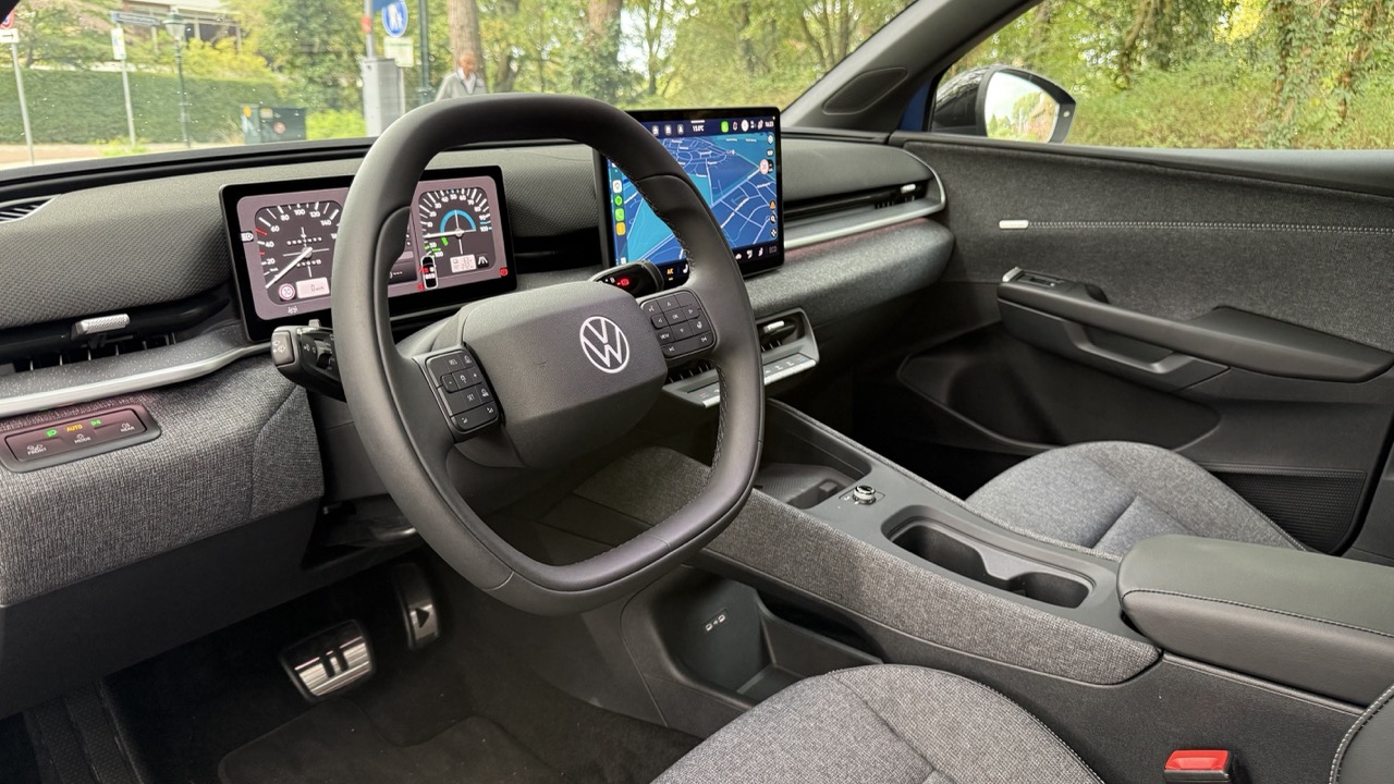 Wnętrze Volkswagena z cyfrowymi zegarami, dużym ekranem nawigacyjnym i szarymi siedzeniami.