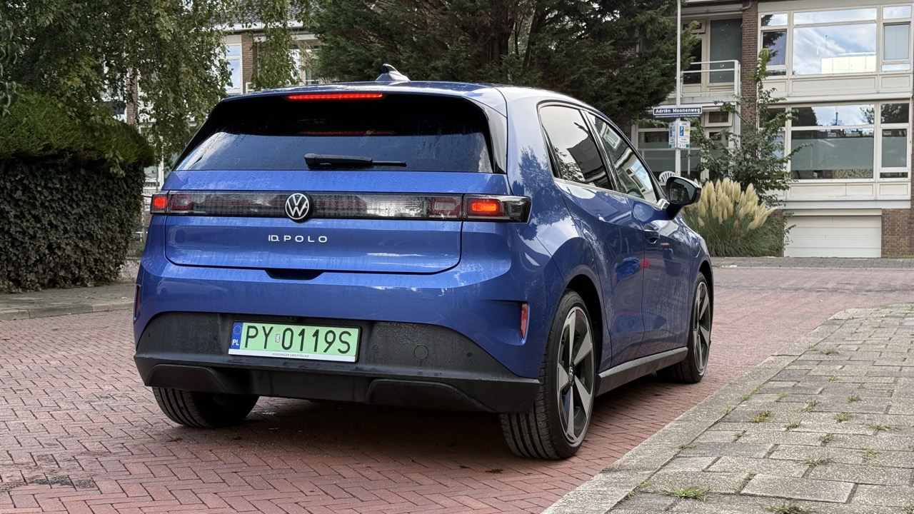 Niebieski Volkswagen Polo z nadwoziem typu hatchback zaparkowany na brukowanej ulicy obok budynków mieszkalnych.