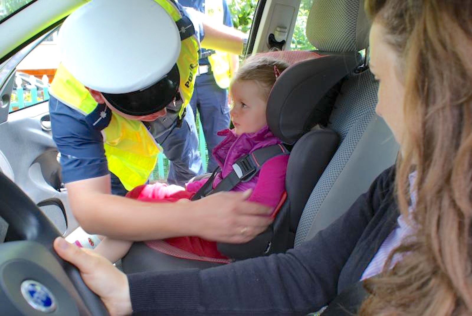 policjant sprawdza fotelik zamontowany na przednim siedzeniu
