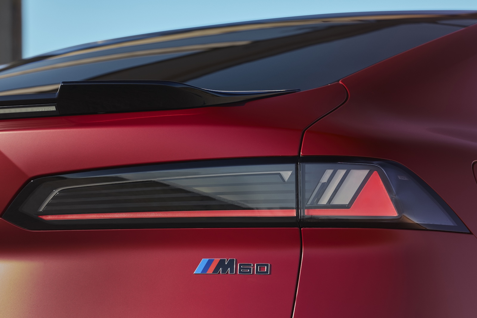 Tylne światło i emblemat M60 na czerwonym BMW iX4.