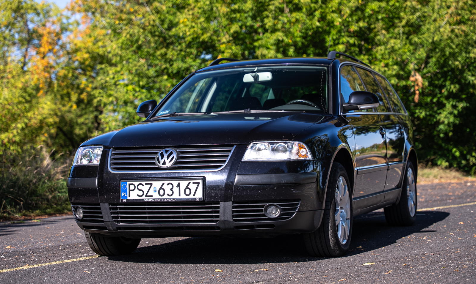 Czarny, używany VW Passat B5 kombi zaparkowany na asfaltowej drodze.