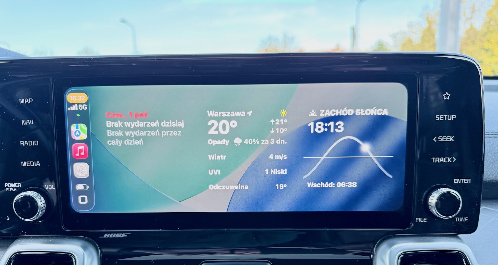 Ekran samochodu: Warszawa, 20°C, 40% prawdopodobieństwa opadów, wiatr 11 km/h, zachód słońca o 18:13.