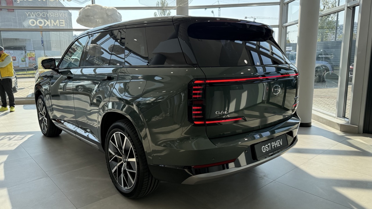 Ciemnozielony SUV GAC GS7 PHEV zaparkowany w salonie.