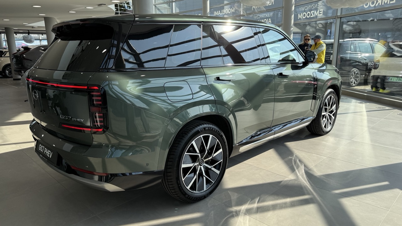 Oliwkowy SUV GAC GS7 PHEV w salonie samochodowym.