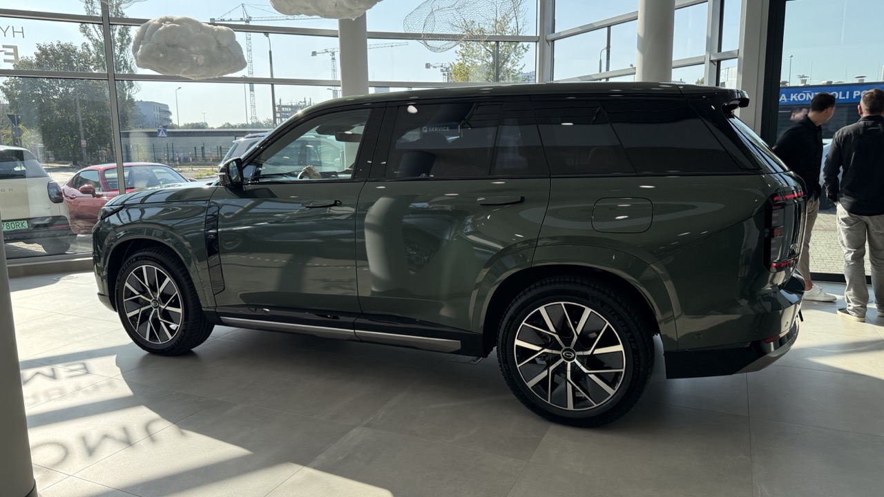 Ciemnozielony SUV zaparkowany w salonie samochodowym.
