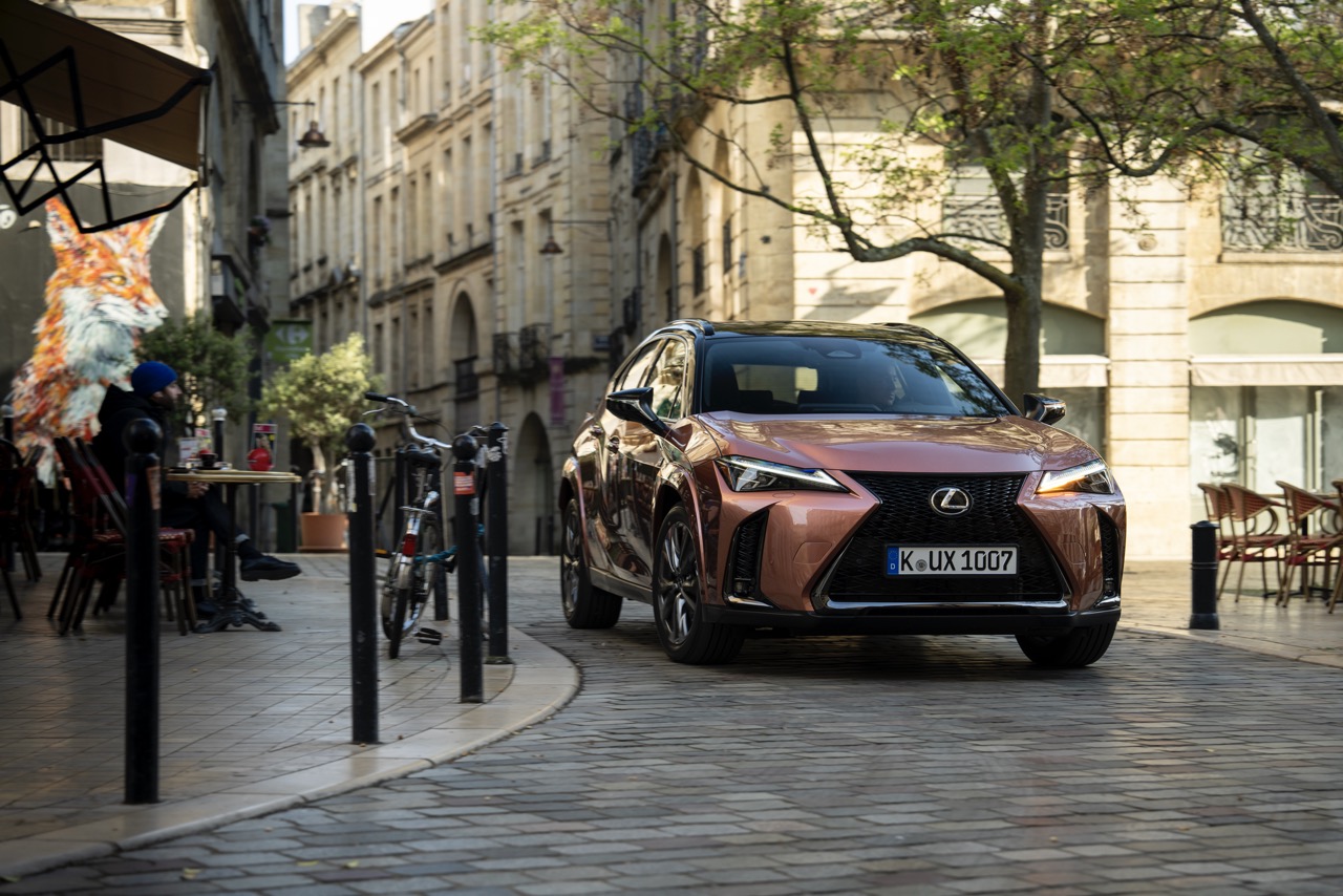 Brązowy Lexus UX zaparkowany na brukowanej ulicy europejskiego miasta.