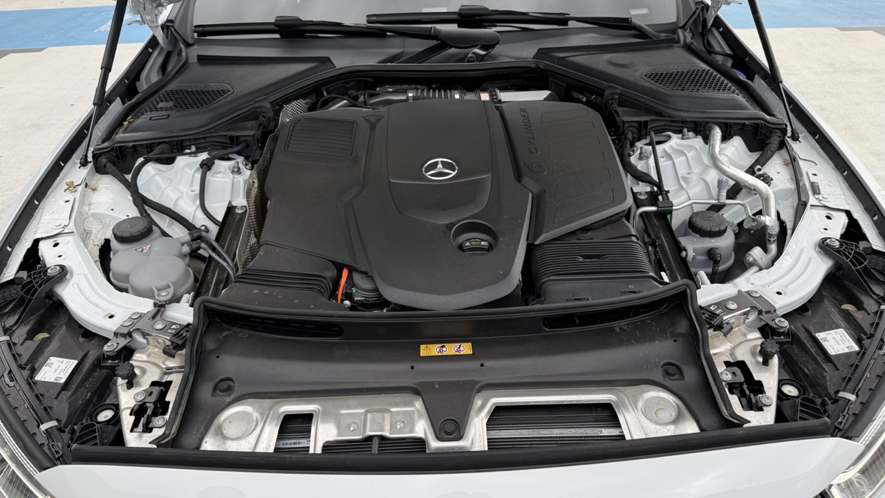 Komora silnika Mercedes-Benz z czarną plastikową pokrywą silnika z logo marki.