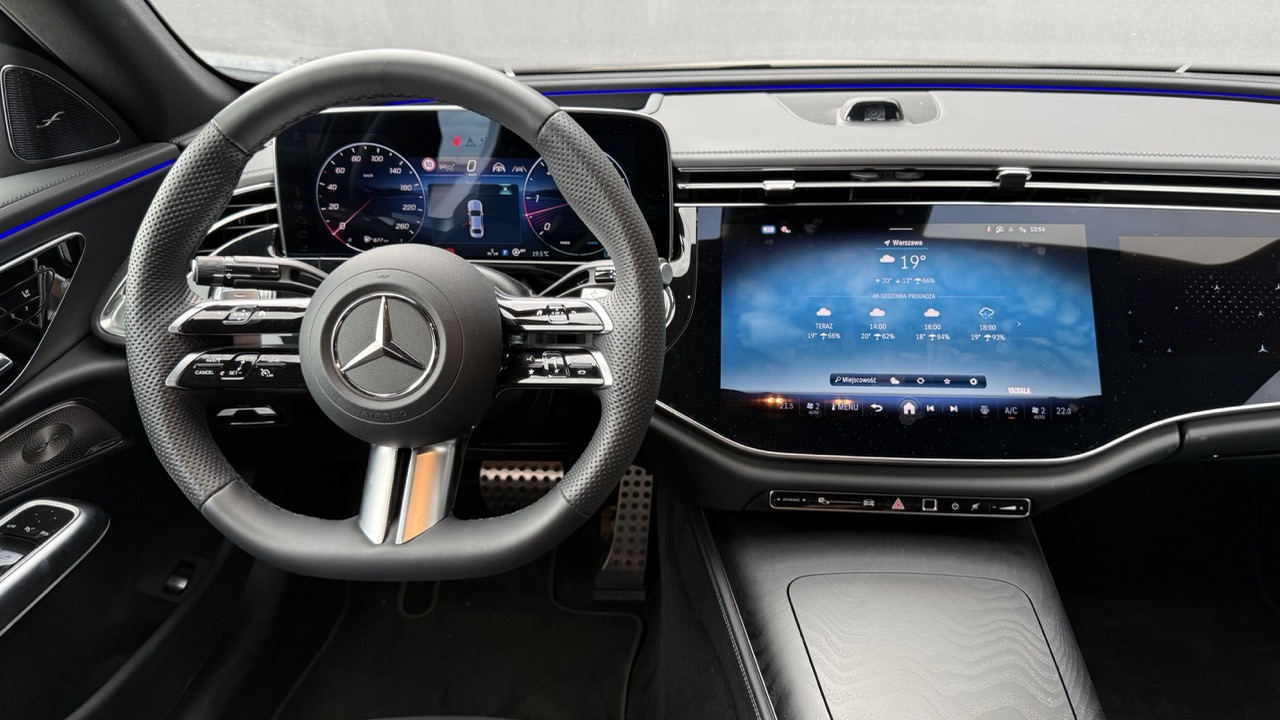 Wnętrze Mercedesa z kierownicą i cyfrowymi ekranami na desce rozdzielczej.